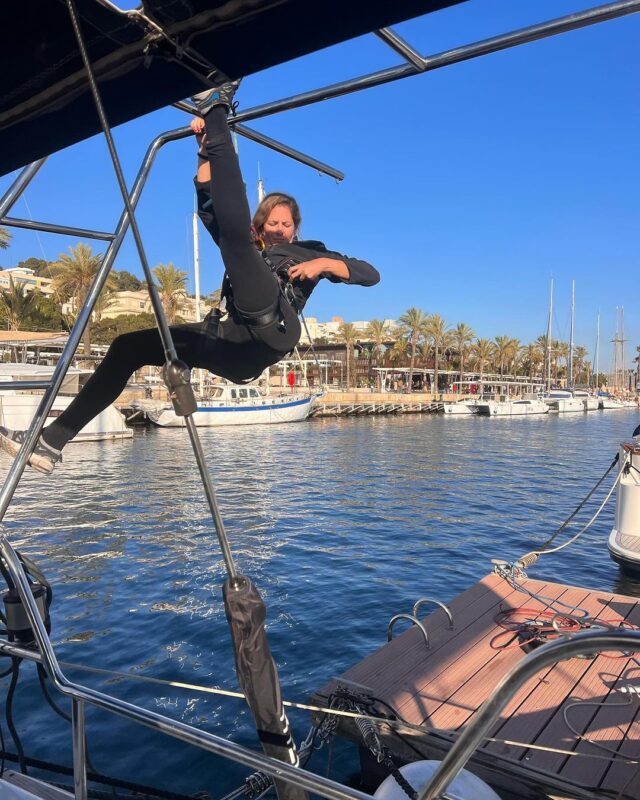 Elena colgada del aparejo del velero en el puerto