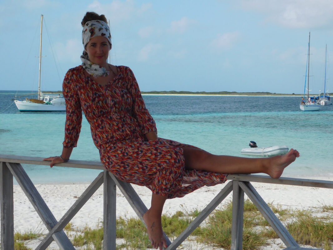 Elena sentada junto a una playa de arena blanca
